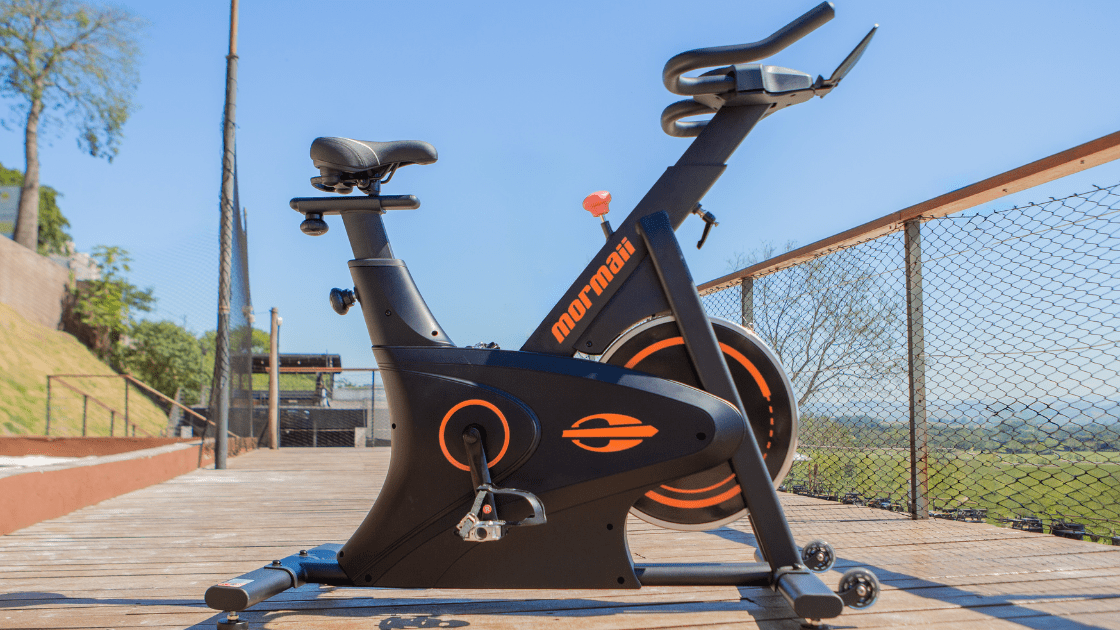 Imagem da Bike Spinning Mormaii Motion-S de lado em um espaço aberto para treino cardio